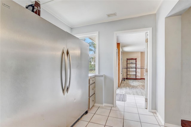 hall featuring light tile patterned floors, baseboards, and visible vents