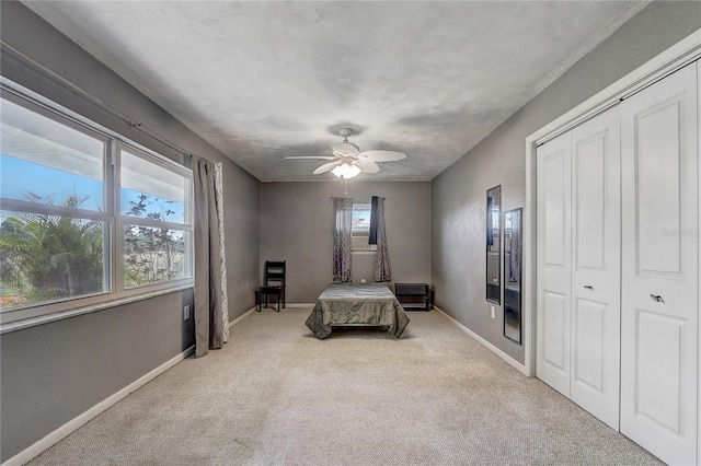 unfurnished bedroom with a closet, baseboards, a ceiling fan, and carpet floors