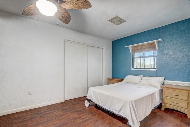 bedroom featuring ceiling fan, dark wood-type flooring, a closet, visible vents, and a textured wall