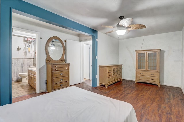 bedroom with a wainscoted wall, connected bathroom, ceiling fan, and wood finished floors