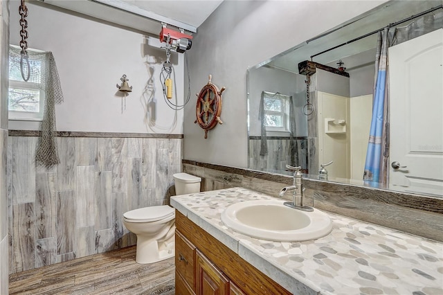 full bath with vanity, a wainscoted wall, toilet, wood finished floors, and tile walls