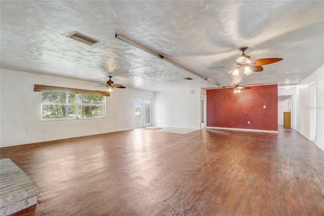 unfurnished living room with a textured ceiling, wood finished floors, ceiling fan, and visible vents
