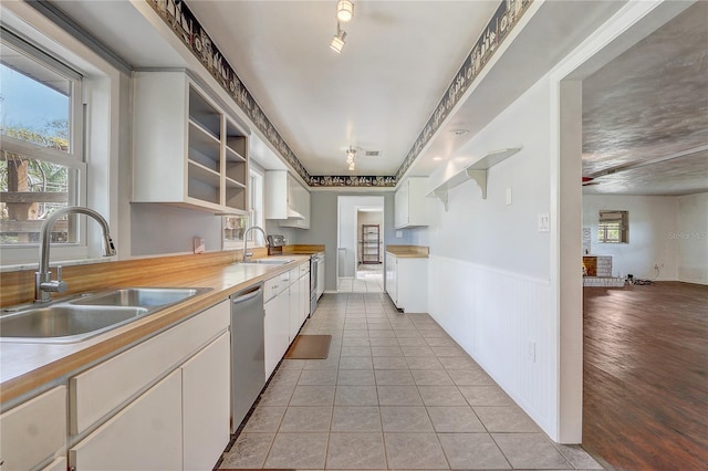 kitchen with dishwasher, a sink, open shelves, and light tile patterned floors