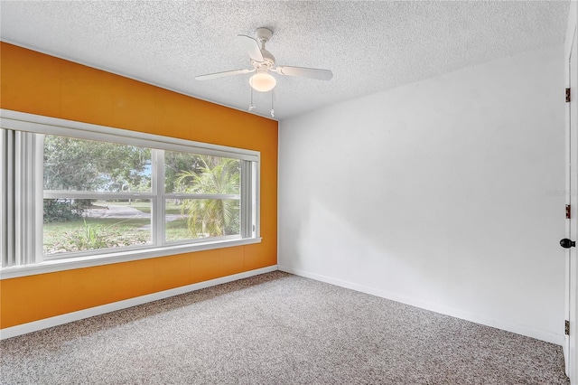 carpeted spare room featuring ceiling fan, baseboards, and a textured ceiling