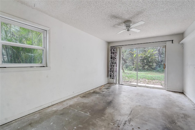 spare room featuring concrete flooring, ceiling fan, baseboards, and a textured ceiling
