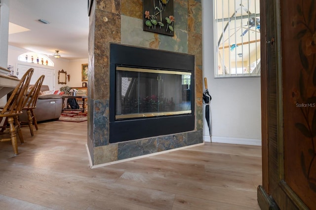 detailed view of ornamental molding, wood finished floors, baseboards, and a multi sided fireplace