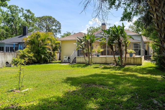 back of property with a lawn, stucco siding, and a chimney
