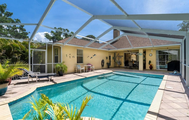 swimming pool with a patio area, a ceiling fan, and a lanai