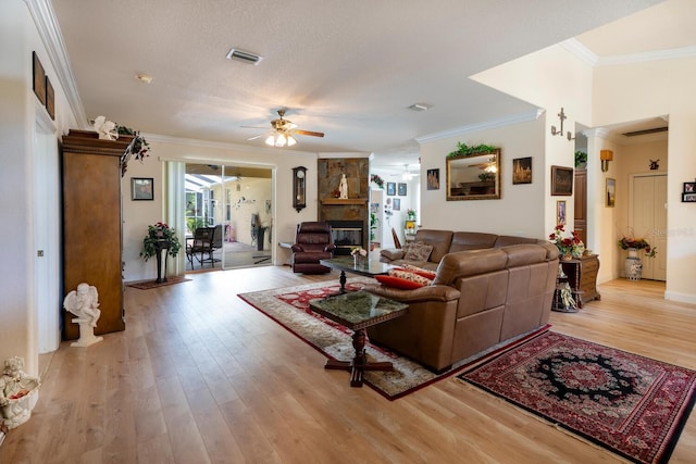 living room featuring a ceiling fan, crown molding, light wood-style flooring, and ornate columns
