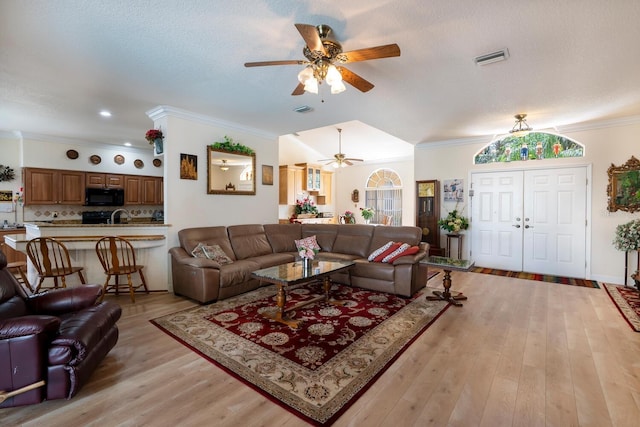living room featuring ceiling fan, crown molding, and light wood finished floors