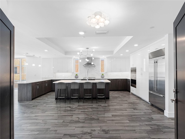 19816 Gulf Blvd Unit 602, Indian Shores, FL 33785 - kitchen with white cabinets, a tray ceiling, dark wood finished floors, modern cabinets, and stainless steel built in fridge
