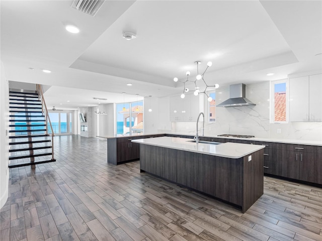 19816 Gulf Blvd Unit 602, Indian Shores, FL 33785 - kitchen with wall chimney range hood, dark brown cabinets, a kitchen island with sink, modern cabinets, and visible vents