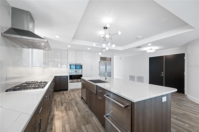 19816 Gulf Blvd Unit 602, Indian Shores, FL 33785 - kitchen featuring wall chimney exhaust hood, stainless steel appliances, white cabinets, modern cabinets, and a raised ceiling