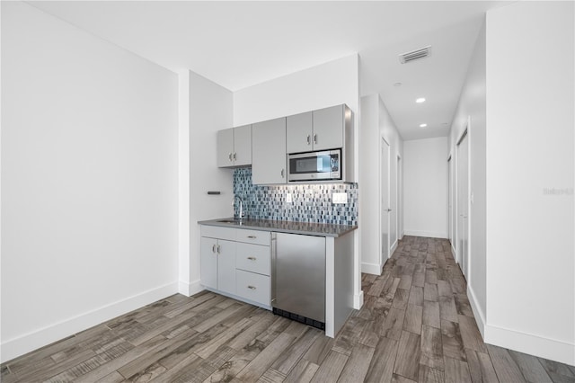 19816 Gulf Blvd Unit 602, Indian Shores, FL 33785 - kitchen with decorative backsplash, stainless steel appliances, light wood finished floors, gray cabinetry, and visible vents