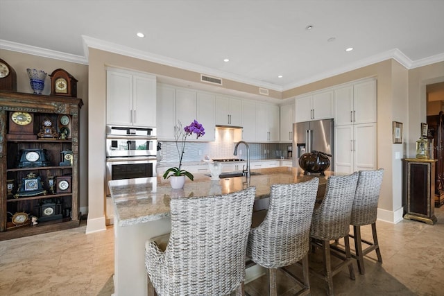 145 Belleview Blvd Unit 201, Belleair, FL 33756 - kitchen with light stone countertops, ornamental molding, white cabinetry, visible vents, and appliances with stainless steel finishes