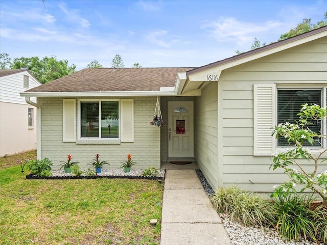 16116 Manorwood Cir, Tampa, FL 33624 - entrance to property featuring a yard, a shingled roof, and brick siding