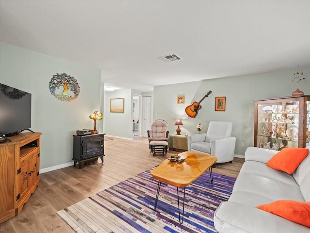 16116 Manorwood Cir, Tampa, FL 33624 - living room featuring visible vents, a wood stove, wood finished floors, and baseboards