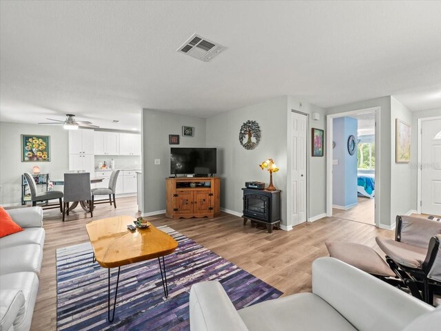 16116 Manorwood Cir, Tampa, FL 33624 - living room featuring baseboards, light wood-type flooring, a ceiling fan, a wood stove, and visible vents