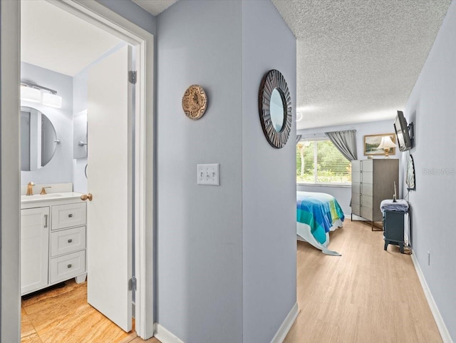 16116 Manorwood Cir, Tampa, FL 33624 - corridor with a textured ceiling, baseboards, and light wood-type flooring