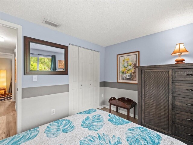 16116 Manorwood Cir, Tampa, FL 33624 - bedroom featuring a textured ceiling, wood finished floors, a closet, and visible vents