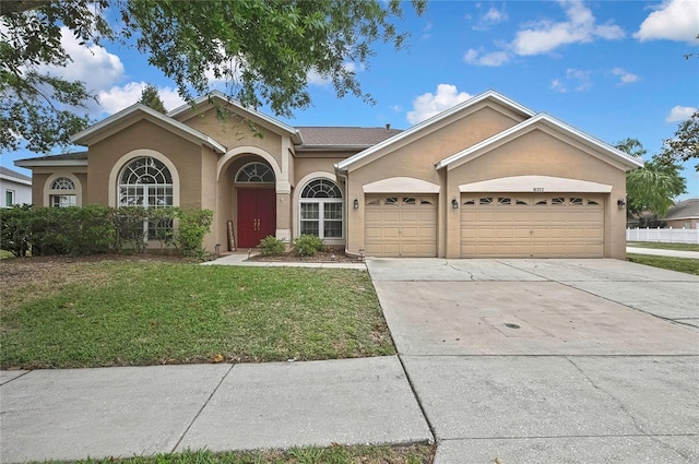 ranch-style house with a front yard, concrete driveway, a garage, and stucco siding