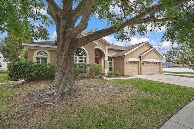 view of front of property featuring stucco siding, driveway, an attached garage, a front lawn, and a shingled roof