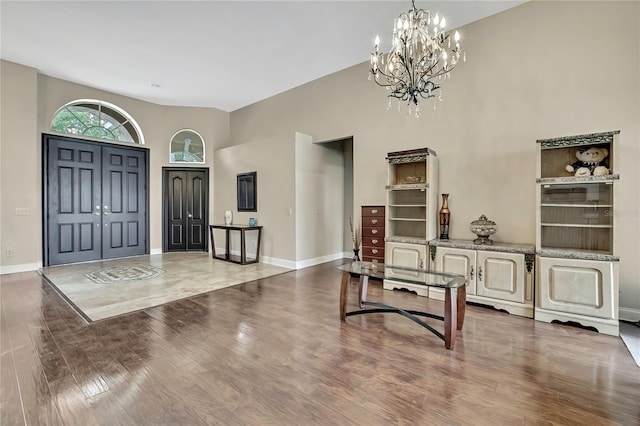 entrance foyer featuring wood finished floors, an inviting chandelier, baseboards, and vaulted ceiling