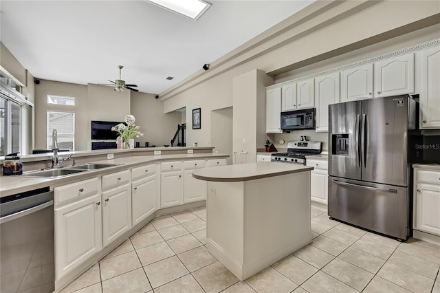 kitchen with a center island, a ceiling fan, light tile patterned flooring, white cabinets, and stainless steel appliances