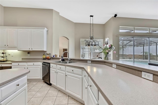 kitchen with arched walkways, a sink, light countertops, dishwashing machine, and pendant lighting