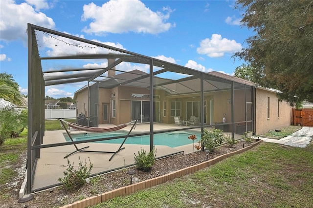 rear view of property with glass enclosure, fence, a patio, stucco siding, and a fenced in pool