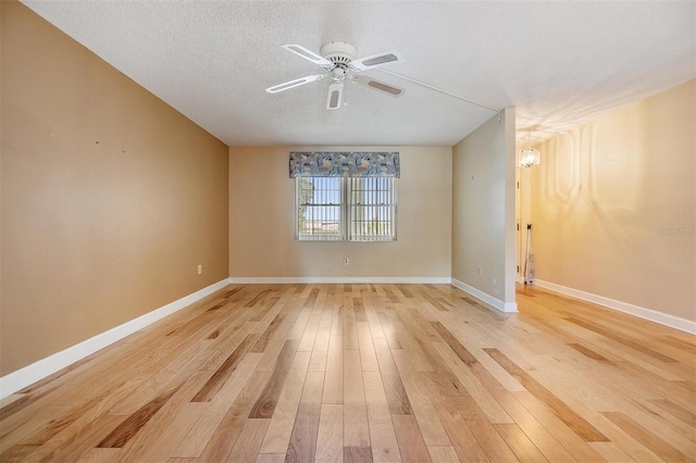 empty room with baseboards, a textured ceiling, light wood-style flooring, and ceiling fan