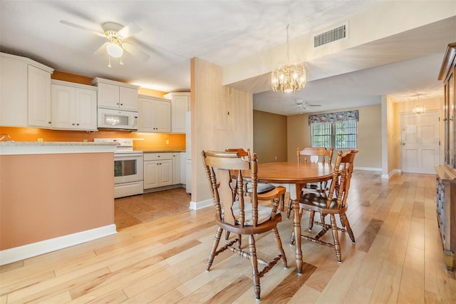dining area featuring baseboards, ceiling fan with notable chandelier, light wood-style flooring, and visible vents