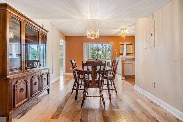 dining room with light wood-style floors, baseboards, electric panel, and ceiling fan with notable chandelier
