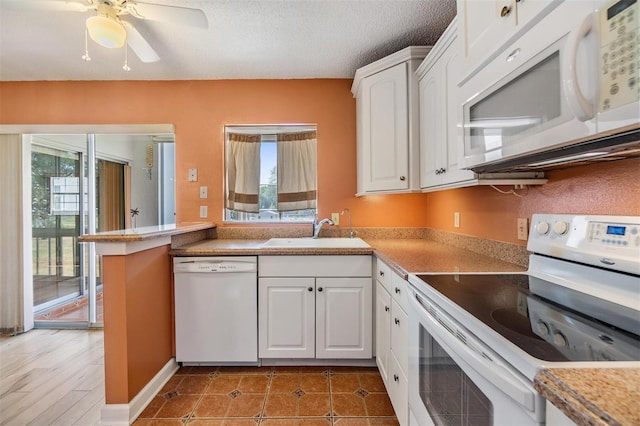 kitchen featuring a sink, white appliances, white cabinetry, and a healthy amount of sunlight
