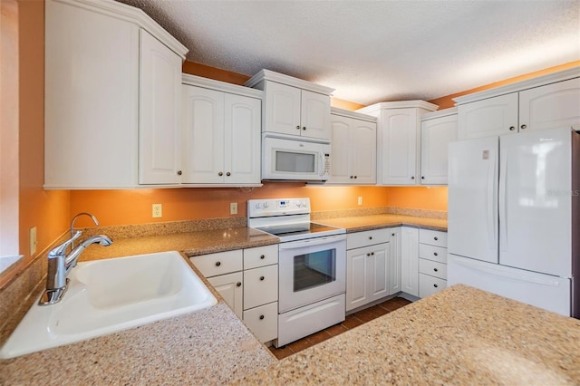 kitchen with white appliances, a textured ceiling, white cabinets, and a sink