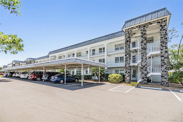 view of building exterior with covered and uncovered parking