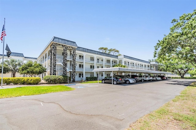 view of building exterior featuring covered and uncovered parking