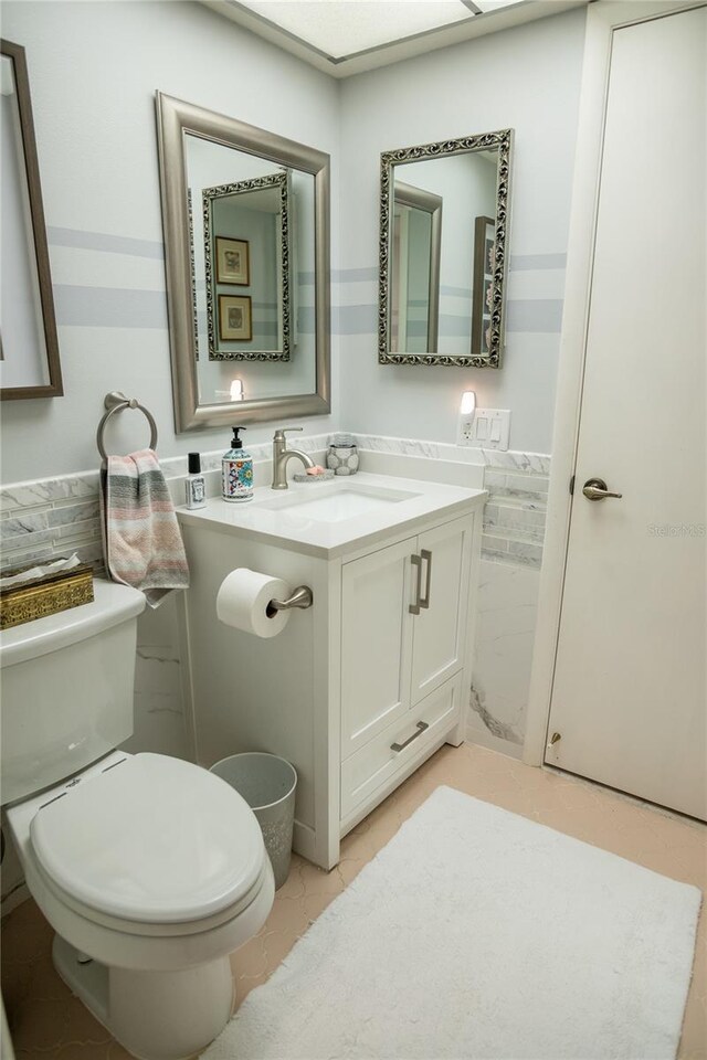 2630 Pearce Dr Unit 104, Clearwater, FL 33764 - bathroom featuring toilet, vanity, and a wainscoted wall