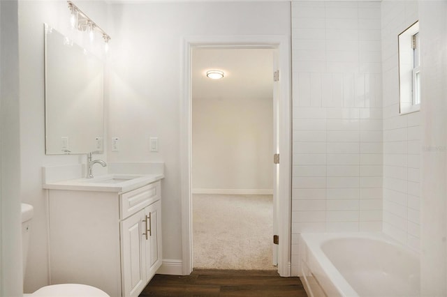 bathroom featuring vanity, toilet, baseboards, wood finished floors, and shower / bathing tub combination
