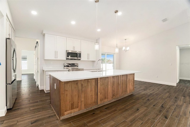 kitchen with a sink, appliances with stainless steel finishes, dark wood finished floors, and light countertops