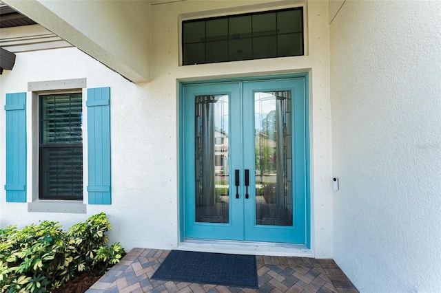 view of exterior entry with french doors and stucco siding