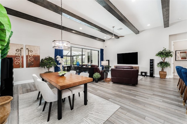 dining room featuring baseboards, visible vents, beamed ceiling, and light wood-style flooring