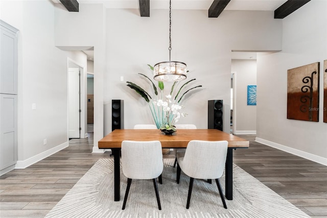 dining space featuring a high ceiling, wood finished floors, beam ceiling, and baseboards