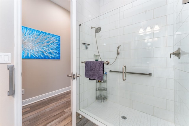 full bathroom with a shower stall, baseboards, and wood finished floors