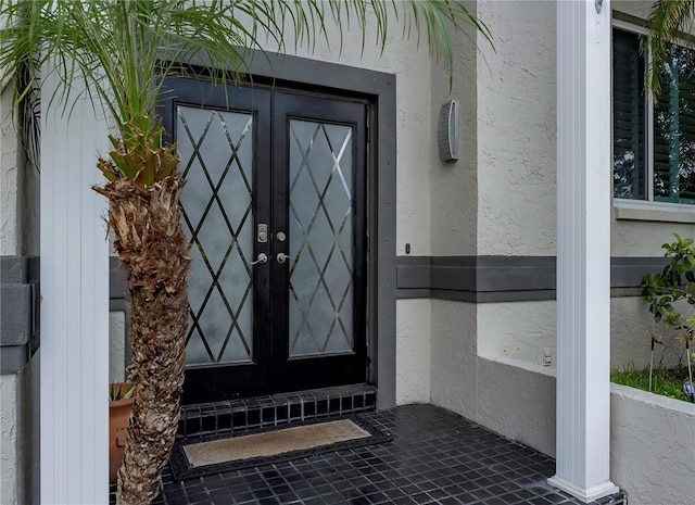 view of exterior entry featuring stucco siding and french doors