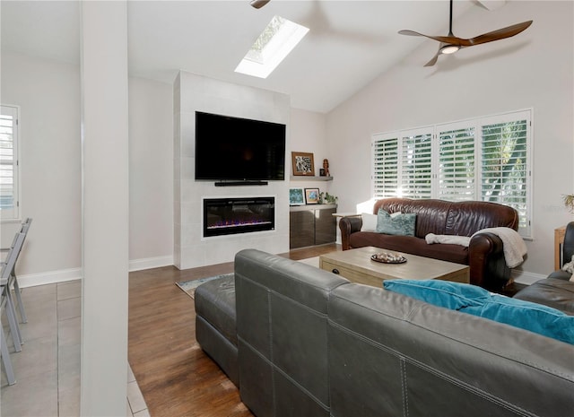 living room featuring a large fireplace, a skylight, a wealth of natural light, and a ceiling fan