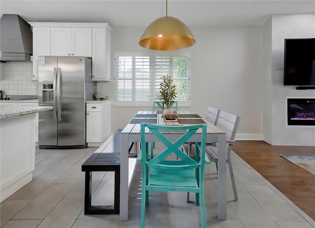 kitchen featuring stainless steel fridge with ice dispenser, white cabinets, custom exhaust hood, and a large fireplace