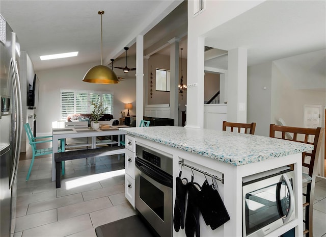 kitchen featuring light stone countertops, light tile patterned floors, stainless steel appliances, and lofted ceiling
