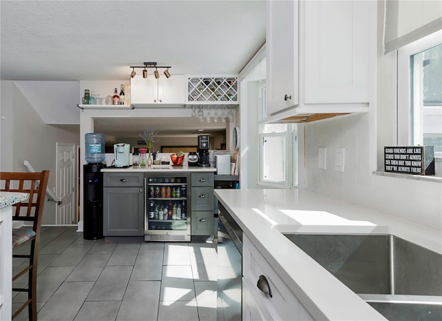 bar featuring wine cooler, light tile patterned floors, a dry bar, and tasteful backsplash