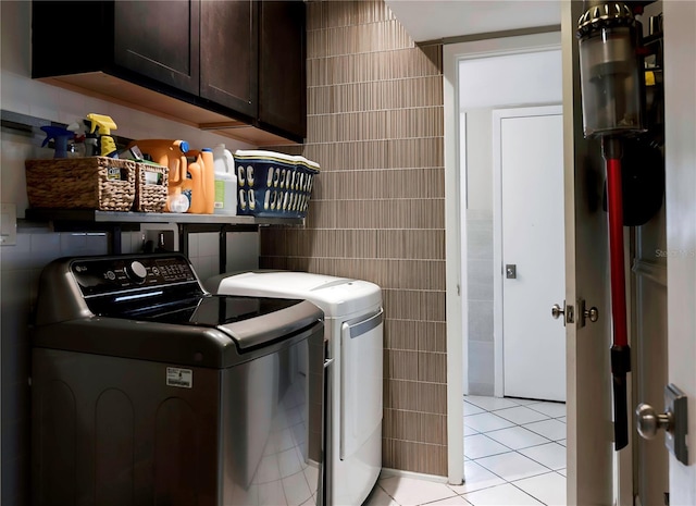 laundry area with tile walls, washer and dryer, light tile patterned flooring, and cabinet space